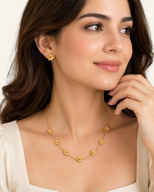 Model wearing gold flower chain necklace and matching gold stud earrings.