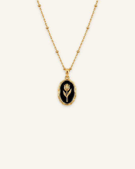 Gold Rose Muse pendant necklace featuring an oval black enamel inlay with a gold flower motif on a beaded satellite chain.