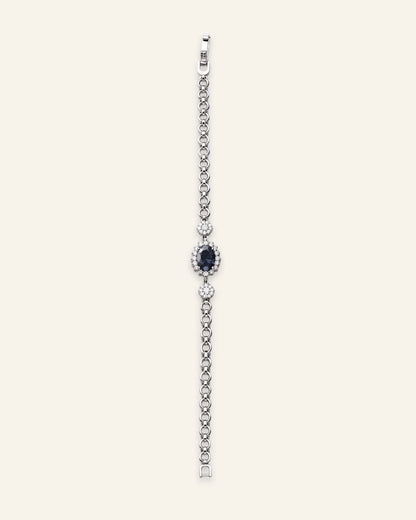 Silver-tone link bracelet featuring a central oval crystal blue stone with a pave halo and delicate crystal accents.