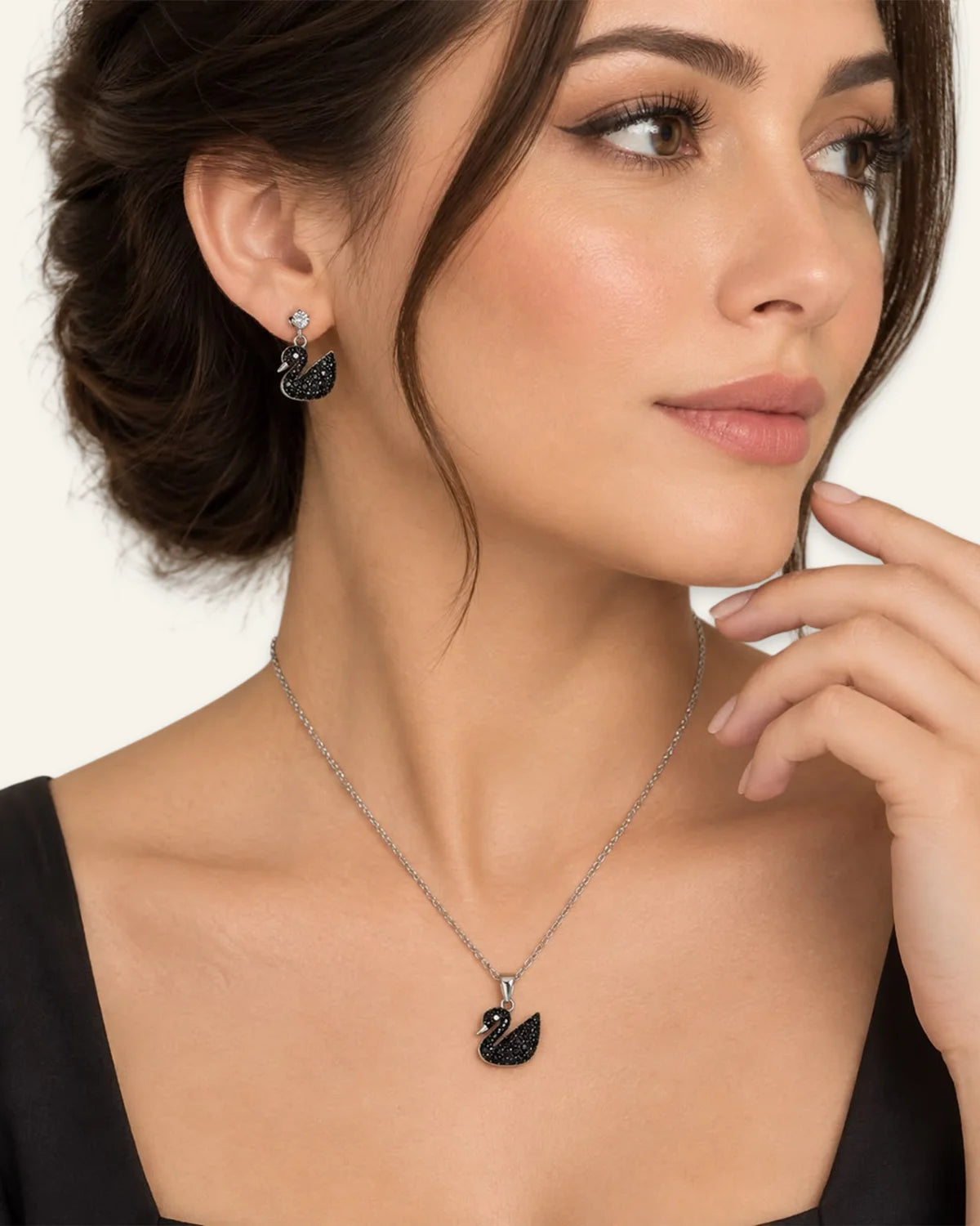 Model wearing a silver chain necklace with a black pave swan pendant and matching black swan drop earrings.