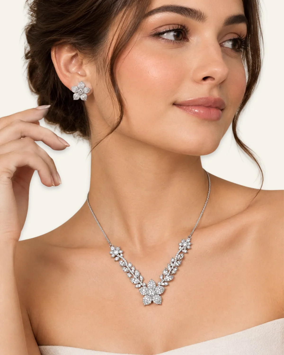 Model wearing a silver crystal floral pendant necklace with leaf vine details and matching five-petal flower stud earrings.