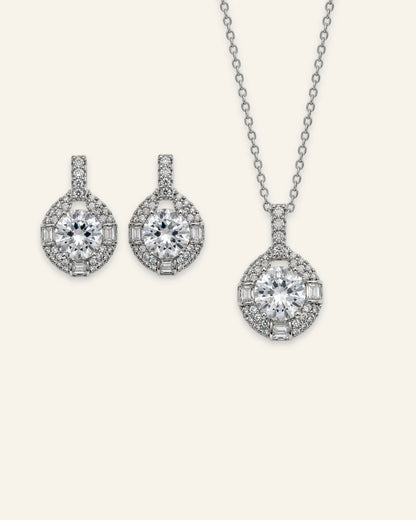 Silver halo pendant necklace and matching drop earrings set featuring round brilliant clear gemstones with pave and baguette accents.