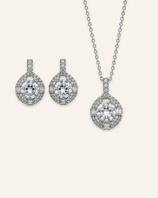 Silver halo pendant necklace and matching drop earrings set featuring round brilliant clear gemstones with pave and baguette accents.