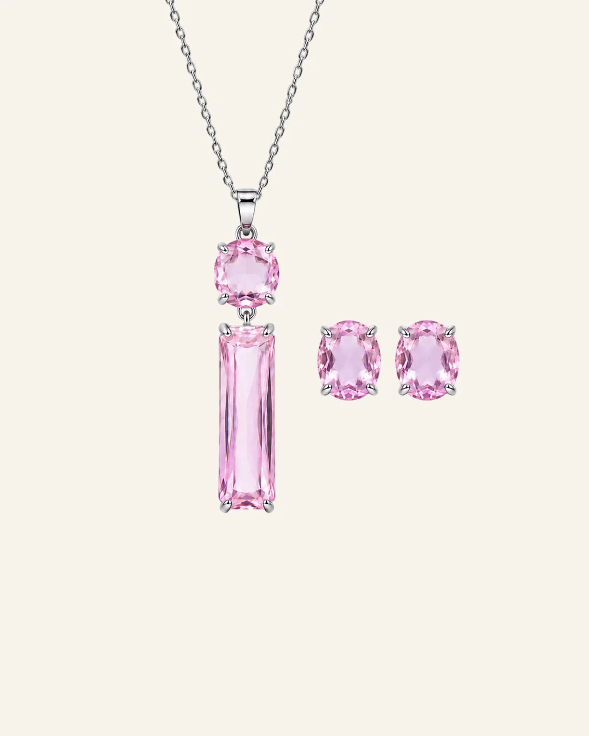 A silver jewelry set featuring a pendant necklace and matching stud earrings with pink gemstones, displayed on a light cream background.