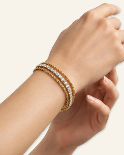 Celeste Crystal Wrap Bracelet, a multi-strand gold-tone bracelet featuring central rows of shining stones flanked by twisted chains, an adjustable clasp extension on a wrist of a against neutral background.