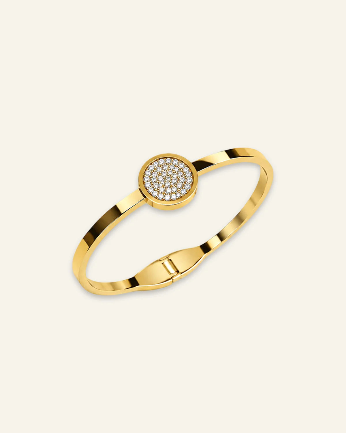 The Celeste Sparkle Bracelet, a polished gold-tone metal hinged bangle featuring a circular centerpiece densely set with clear pave crystals that catch the light, displayed on a clean ivory background.