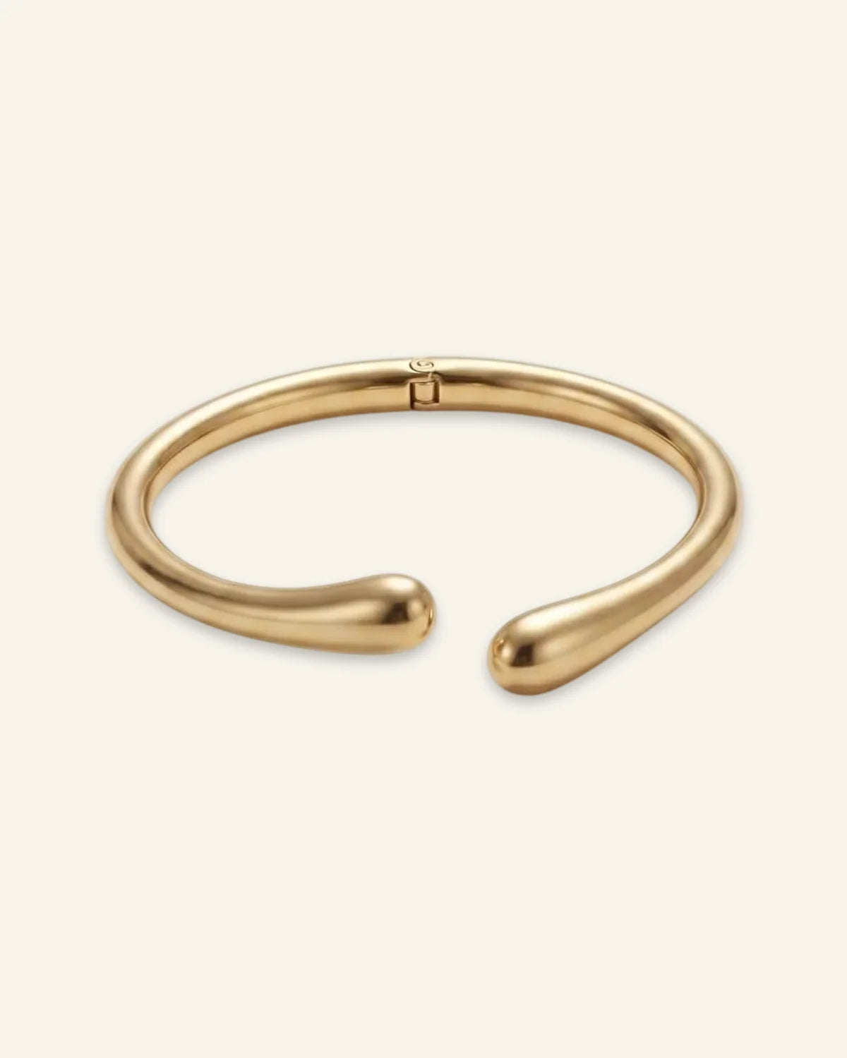 Duo Curve Bracelet, an open gold-tone metal cuff featuring smooth, teardrop-shaped terminals and a hinged closure, displayed on a clean neutral background.