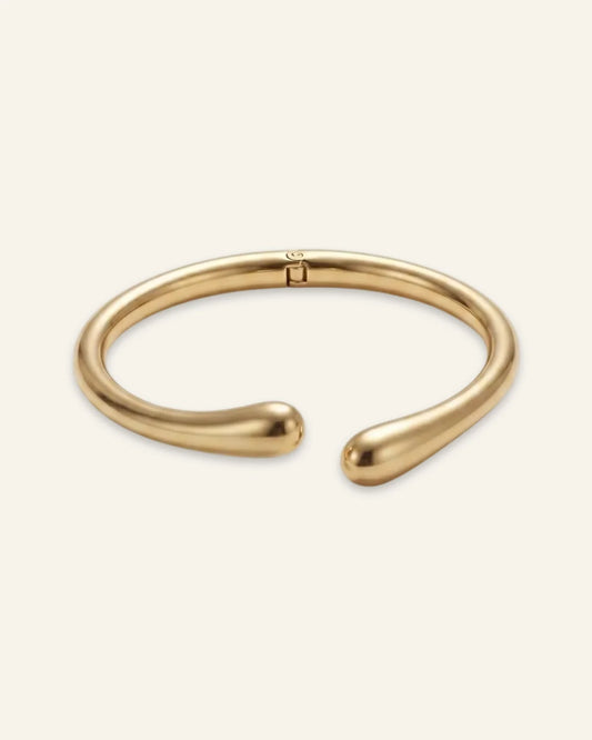Duo Curve Bracelet, an open gold-tone metal cuff featuring smooth, teardrop-shaped terminals and a hinged closure, displayed on a clean neutral background.