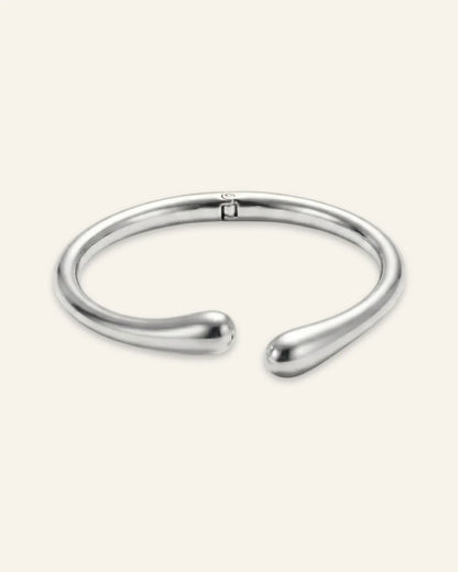 Duo Curve Bracelet, an open silver-tone metal cuff featuring smooth, teardrop-shaped terminals and a hinged closure, displayed on a clean neutral background.