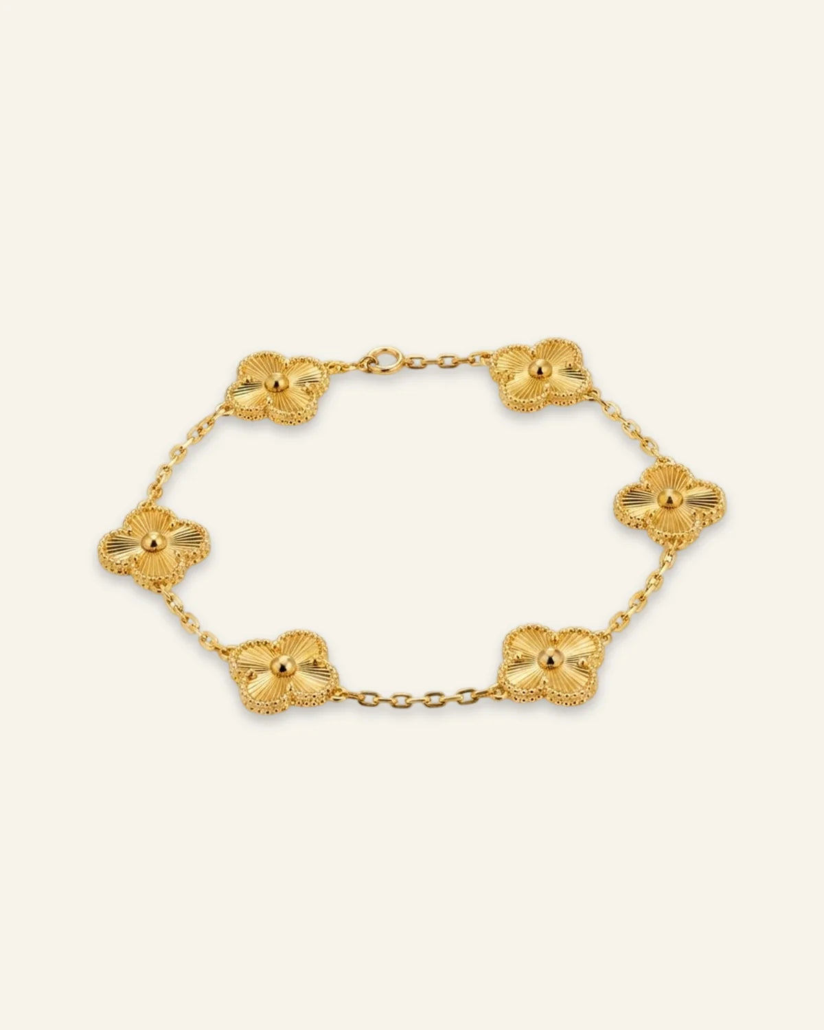 Floral Emblem Bracelet featuring leaf clover motifs with radiating lines and beaded borders on a delicate gold-tone chain against a soft ivory background.