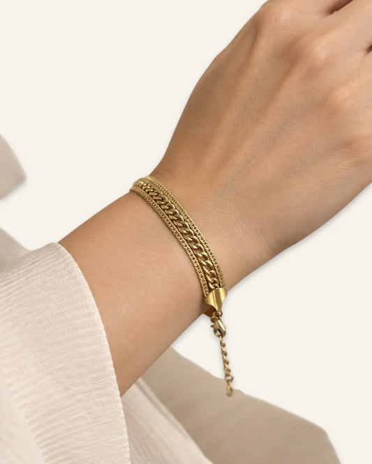 Golden Trinity Chain Bracelet, a multi-strand layered gold-tone chain bracelet featuring mixed link styles and an adjustable clasp extension, worn on a wrist with clean neutral background.