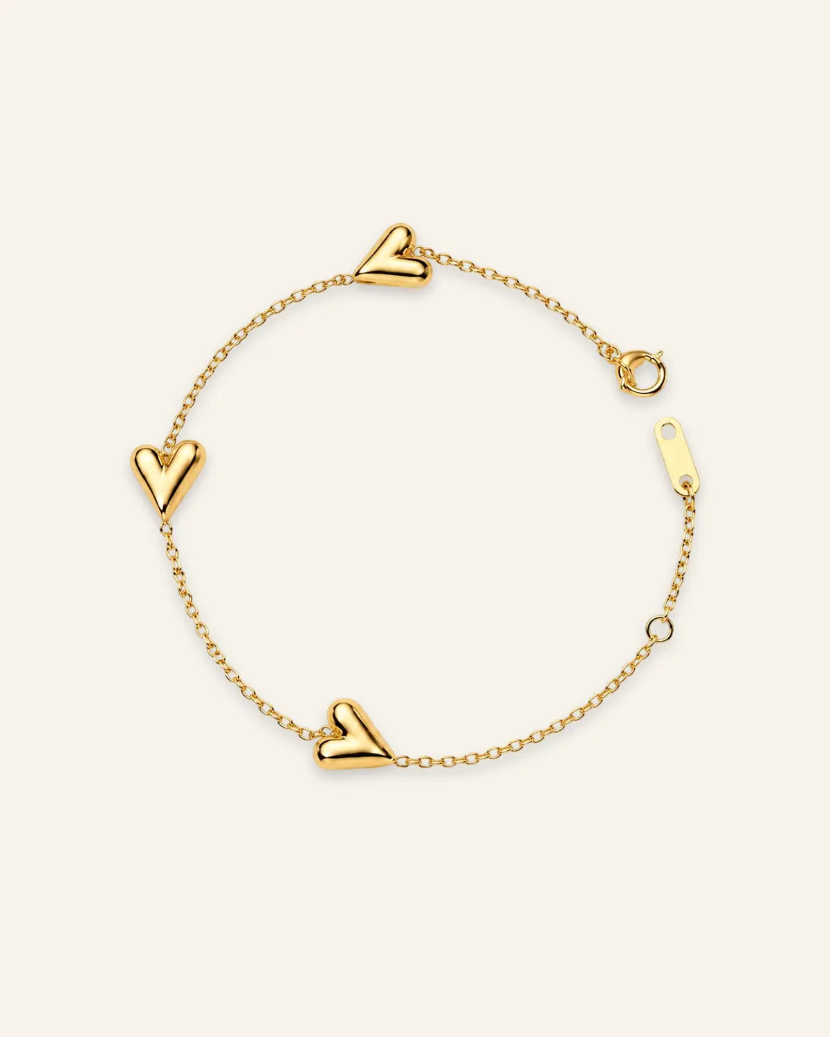 A delicate gold chain bracelet featuring three polished heart charms spaced along the chain, displayed on a clean, solid off-white background.