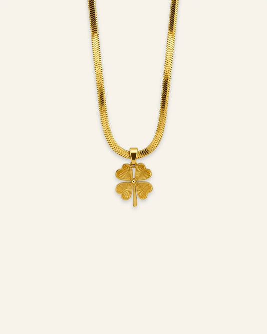 Gold four-leaf lucky clover pendant necklace with a textured charm on a flat herringbone chain.