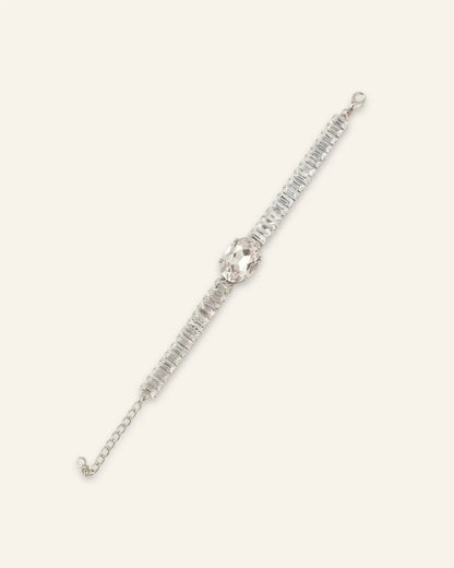 Midnight Luxe Bracelet, a silver-tone crystal line bracelet featuring a large central crystal oval gemstone flanked by rows of rectangular-cut clear stones and an adjustable chain extension on a neutral background.