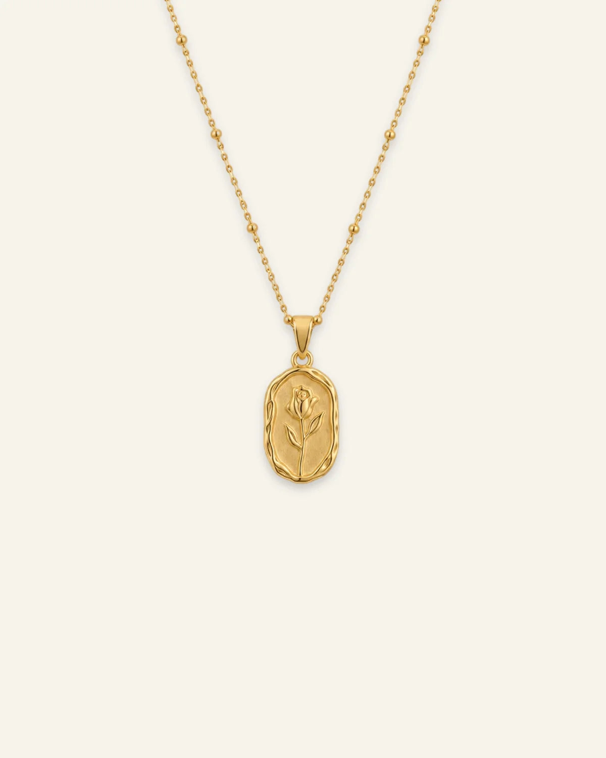 Gold Rose Muse pendant necklace featuring a textured oval pendant with an embossed rose flower motif on a beaded satellite chain.