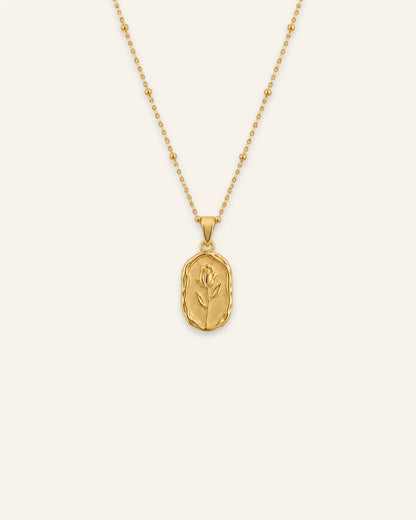 Gold Rose Muse pendant necklace featuring a textured oval pendant with an embossed rose flower motif on a beaded satellite chain.