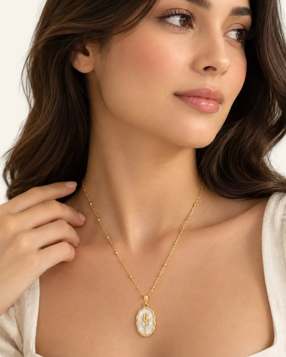 Woman wearing the white mother-of-pearl Rose Muse pendant necklace showing the oval floral pendant styling on the neck.