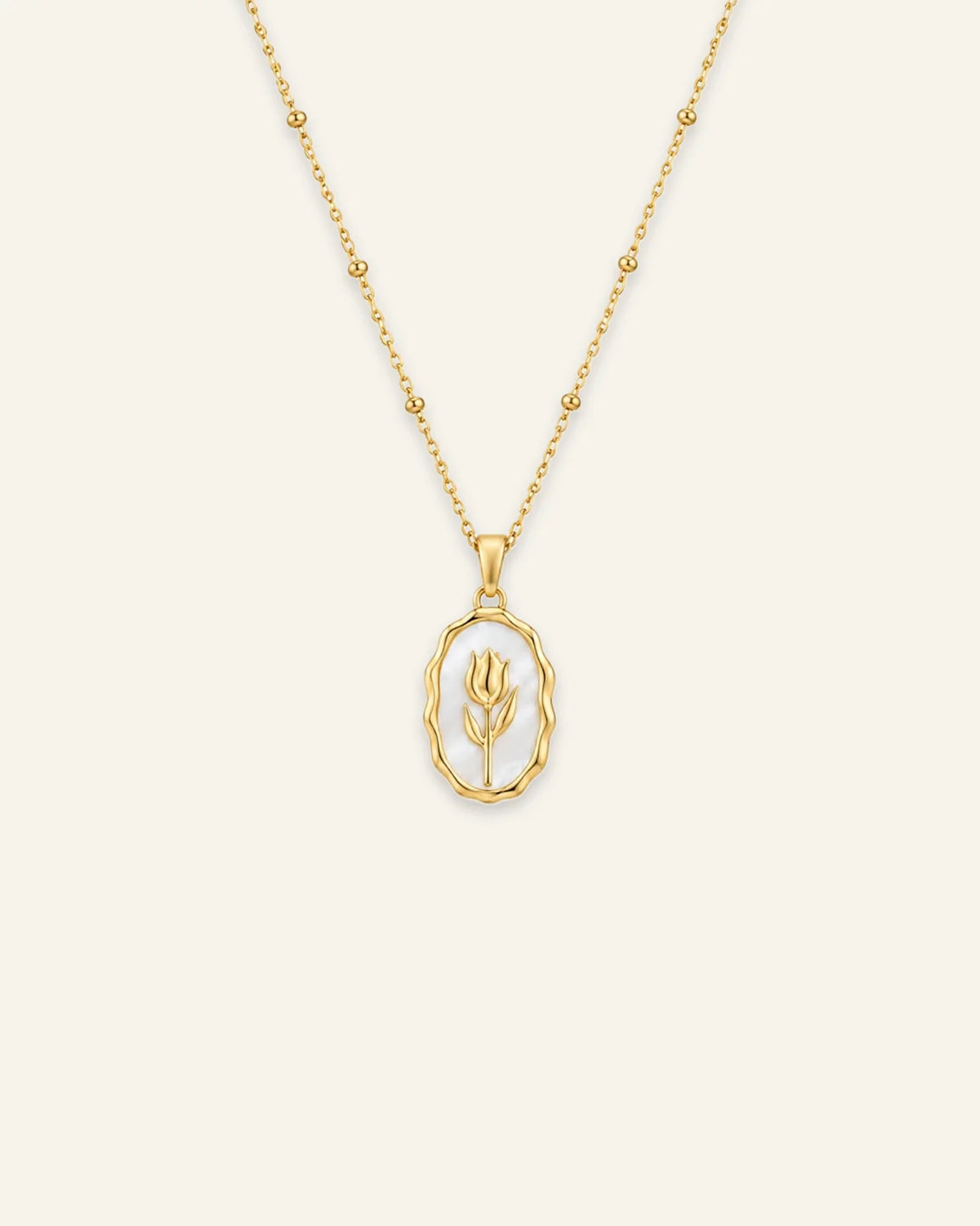 Gold Rose Muse pendant necklace featuring an oval white mother-of-pearl inlay with a gold flower motif on a beaded satellite chain.