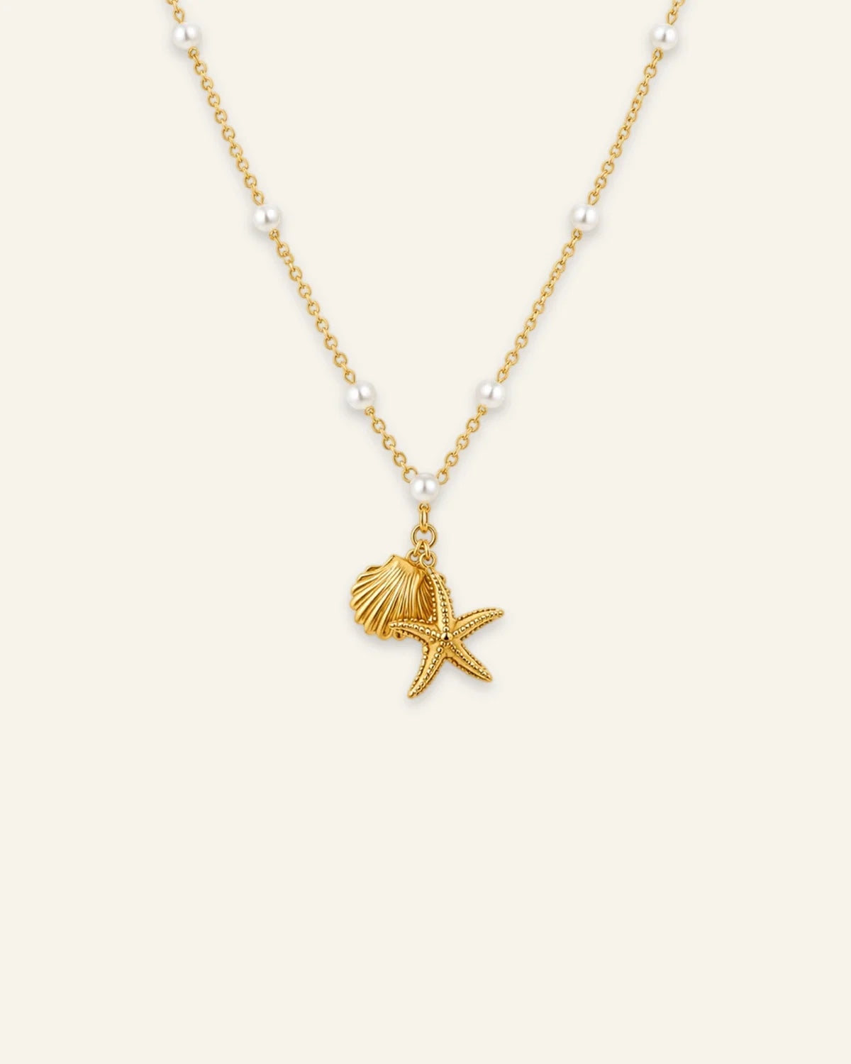 Gold link chain necklace featuring spaced pearl beads and dangling starfish and scalloped seashell charms.